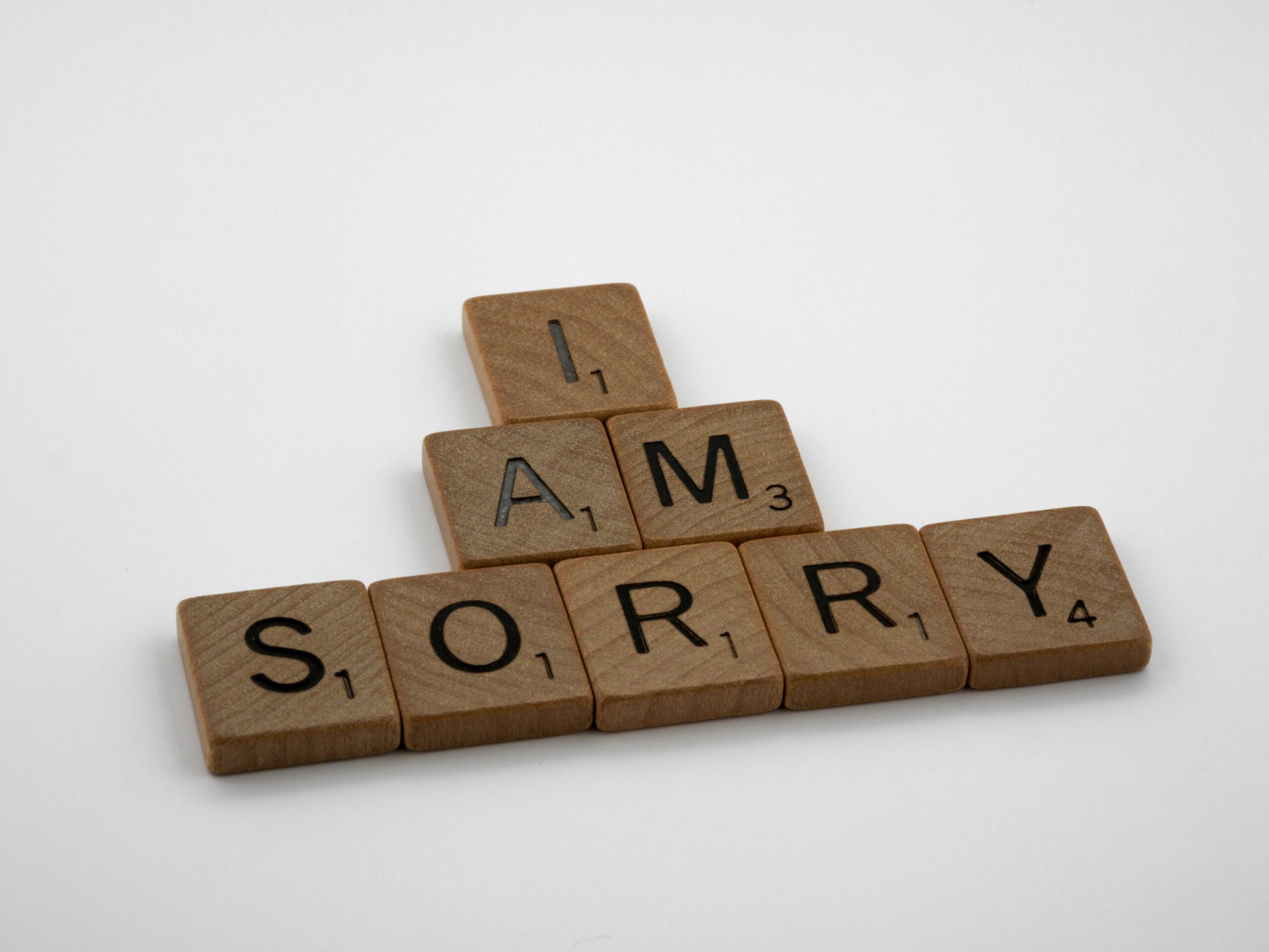 Wooden Scrabble tiles arranged to say 'I Am Sorry' on a clean white background, conveying a message of apology.